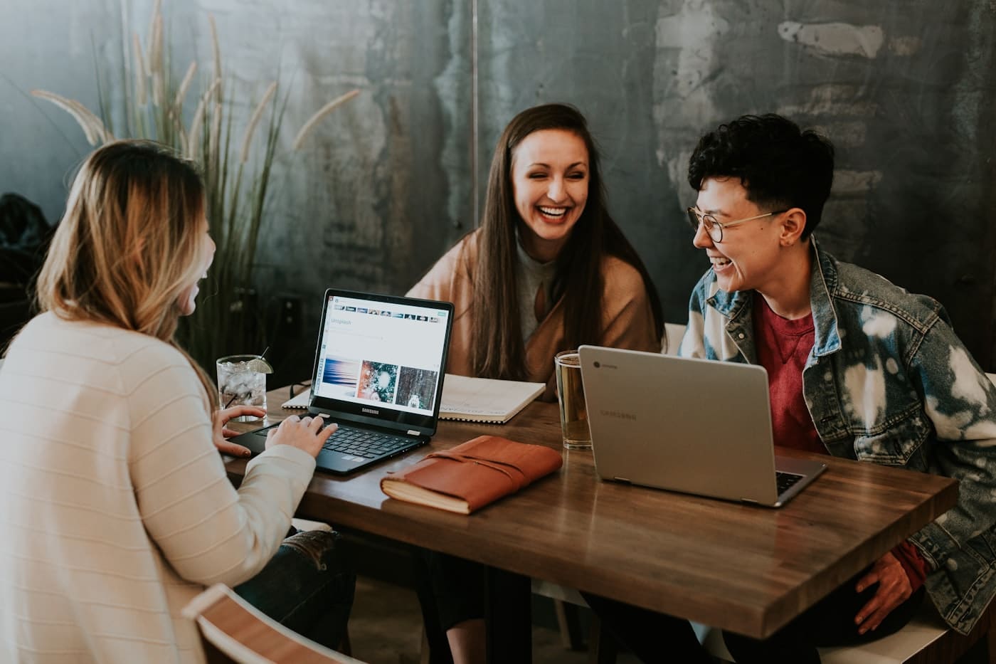 A counsellor mentoring two students over a laptop